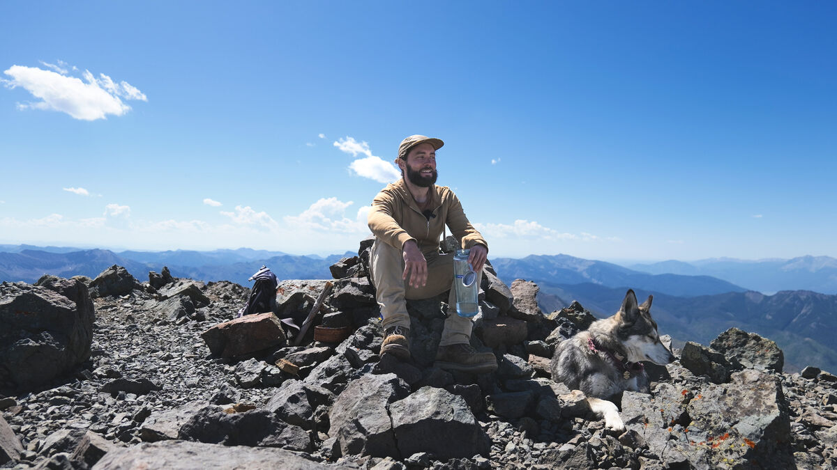 Josh and his wolf on a mountain summit